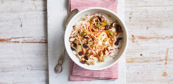 A bowl of oatmeal topped with nuts and raisins