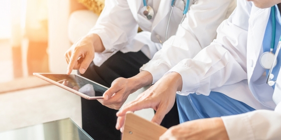 Two doctors using a tablet computer to access medical records and collaborate on patient care.
