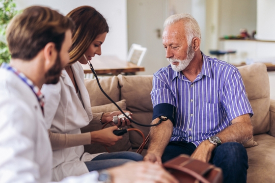 A doctor measures the blood pressure of an elderly man using a sphygmomanometer, ensuring his health is monitored properly.
