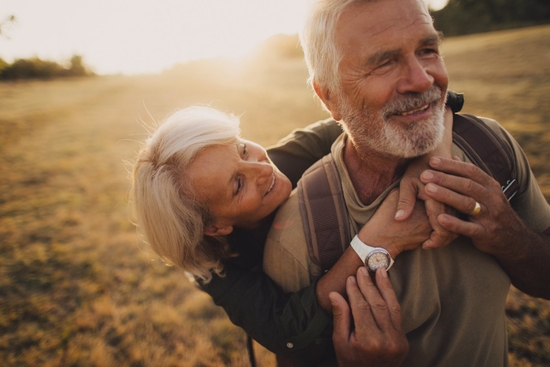 An elderly couple embracing at sunset