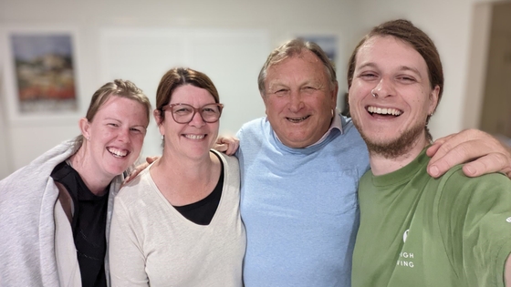 A group of people putting their arms around each other shoulders and smiling