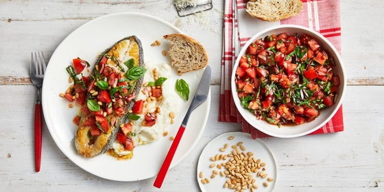 Two plates with a variety of fish and vegetables beautifully arranged on them, creating a colorful and appetizing meal