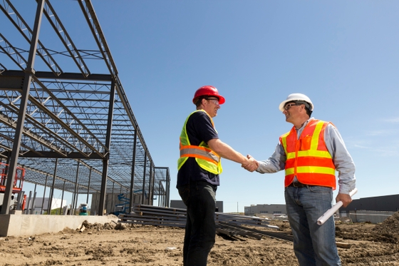 Two men shaking hands in a professional setting, symbolizing a successful business deal.