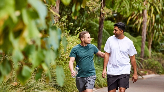 Two men walking and talking in the park, sharing their experiences of heart health